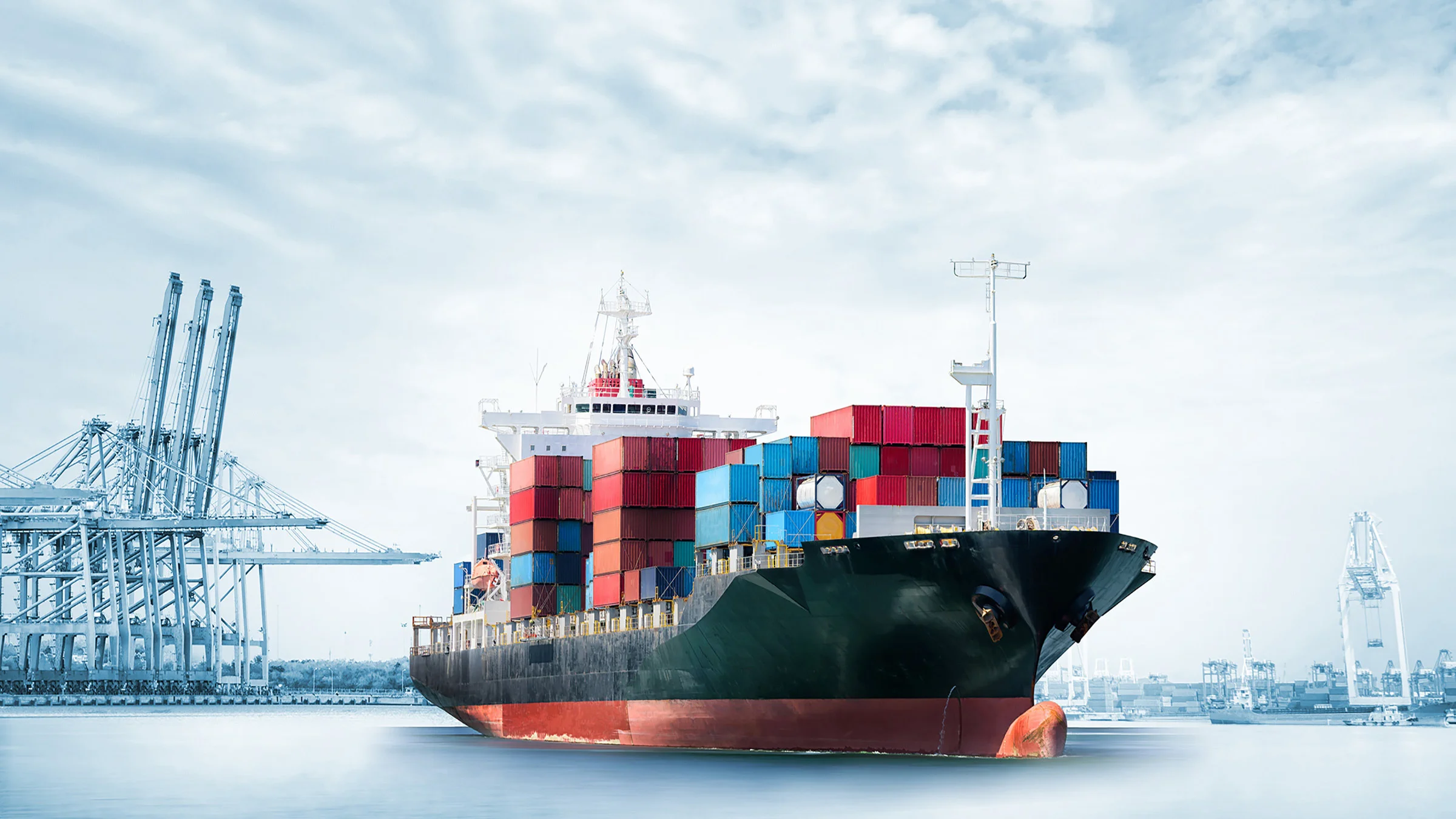 Large cargo ship loaded with containers next to a crane