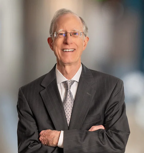 Larry Cumming standing with arms crossed in pinstriped blazer