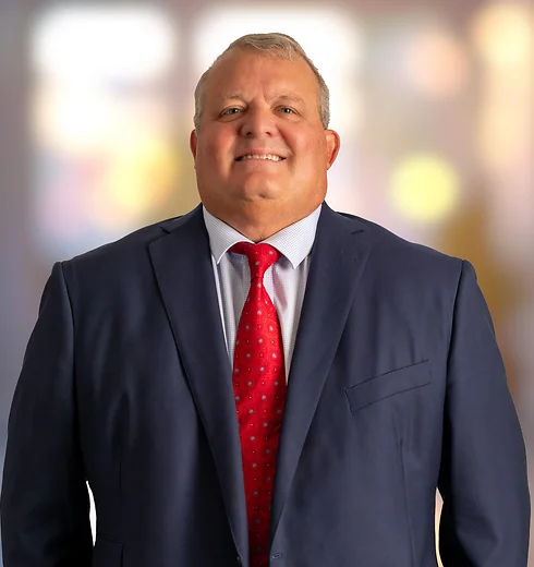 Braxton McKee smiling in a dark suit and red tie