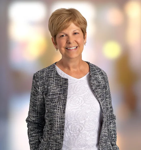 Laurie Claywell smiling in a white top and black and gray sweater