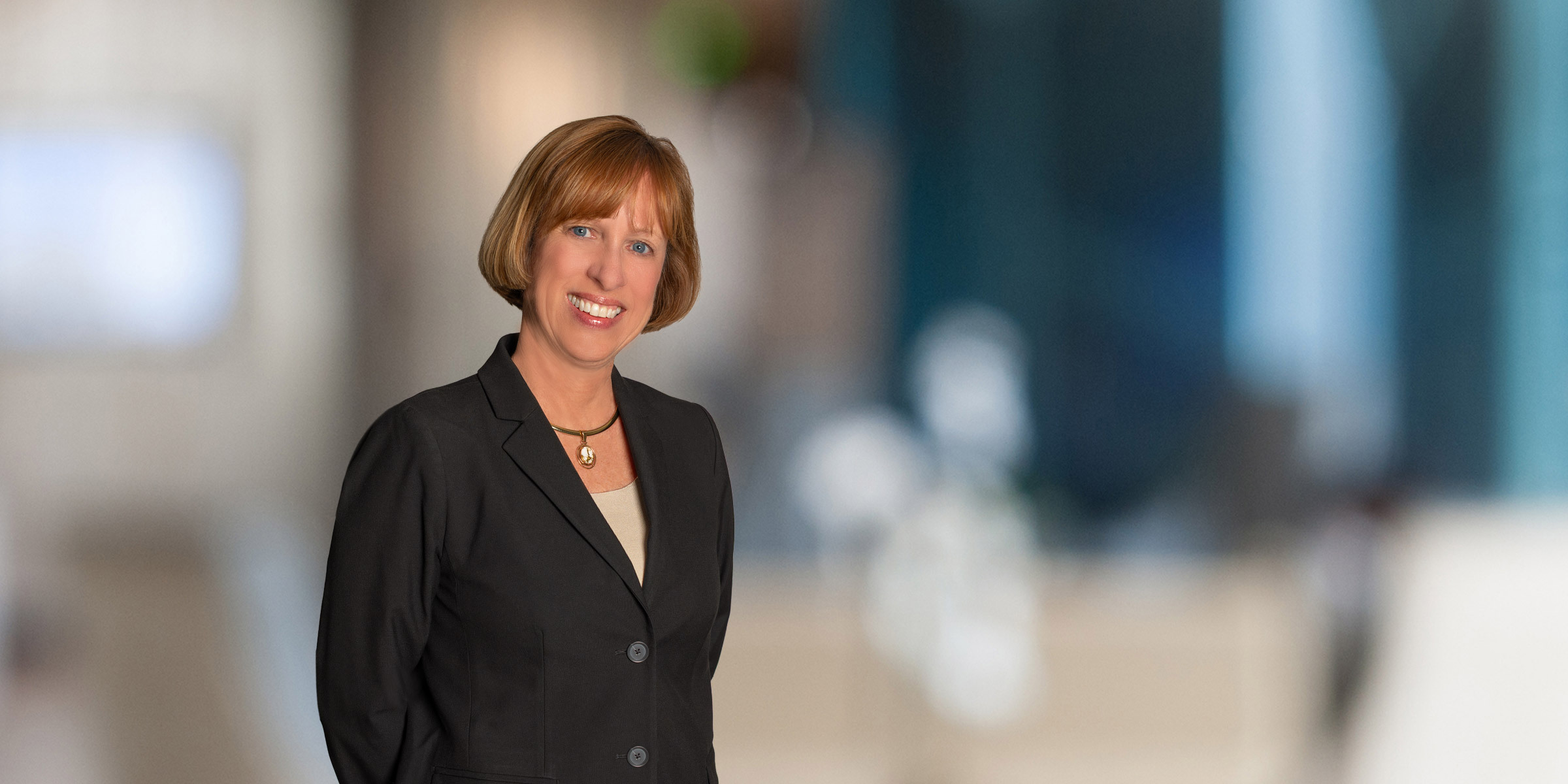 Susanna Hickman smiling with hands behind her back, in black blazer