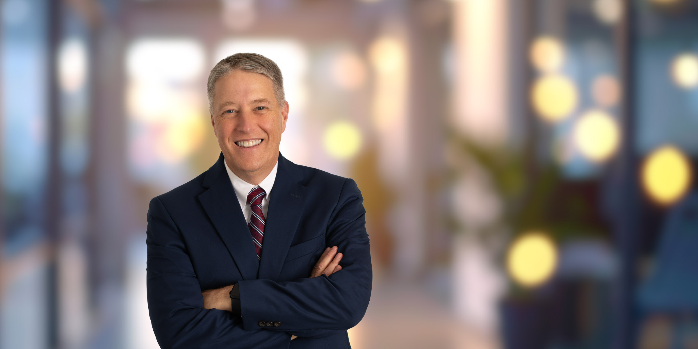 Scott Seymour smiling in a dark blue suit with a red tie