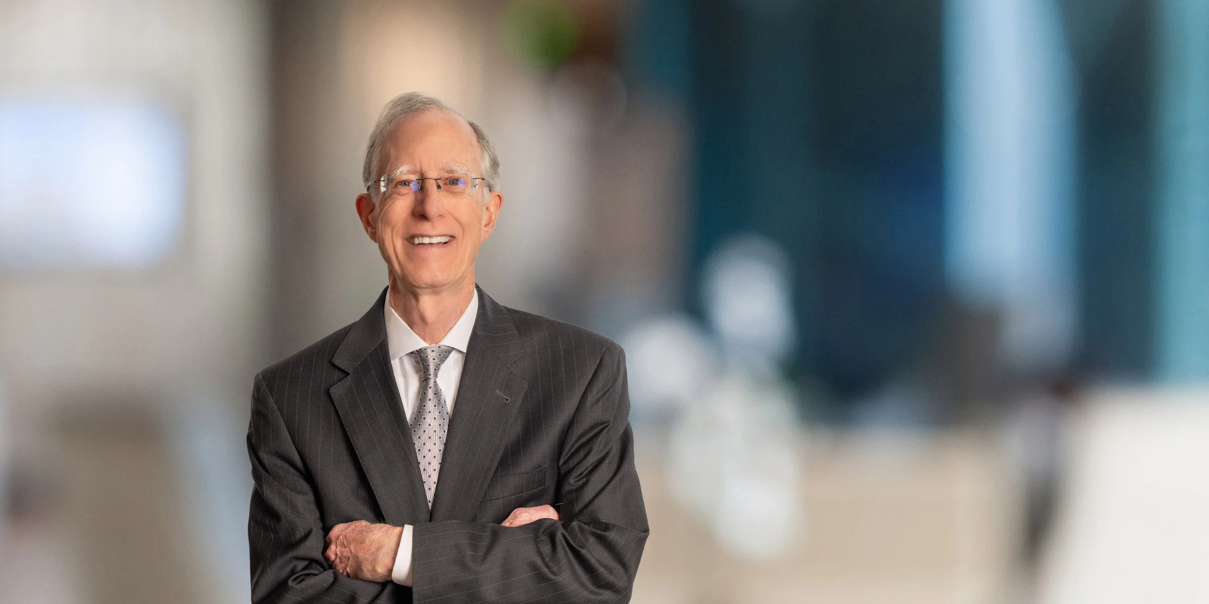Larry Cumming standing with arms crossed in pinstriped blazer