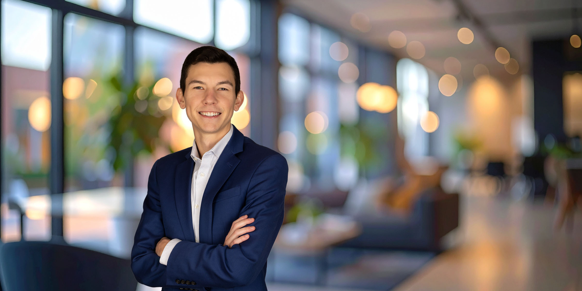 Grayson Owens in a dark blue jacket and white shirt with his arms crossed