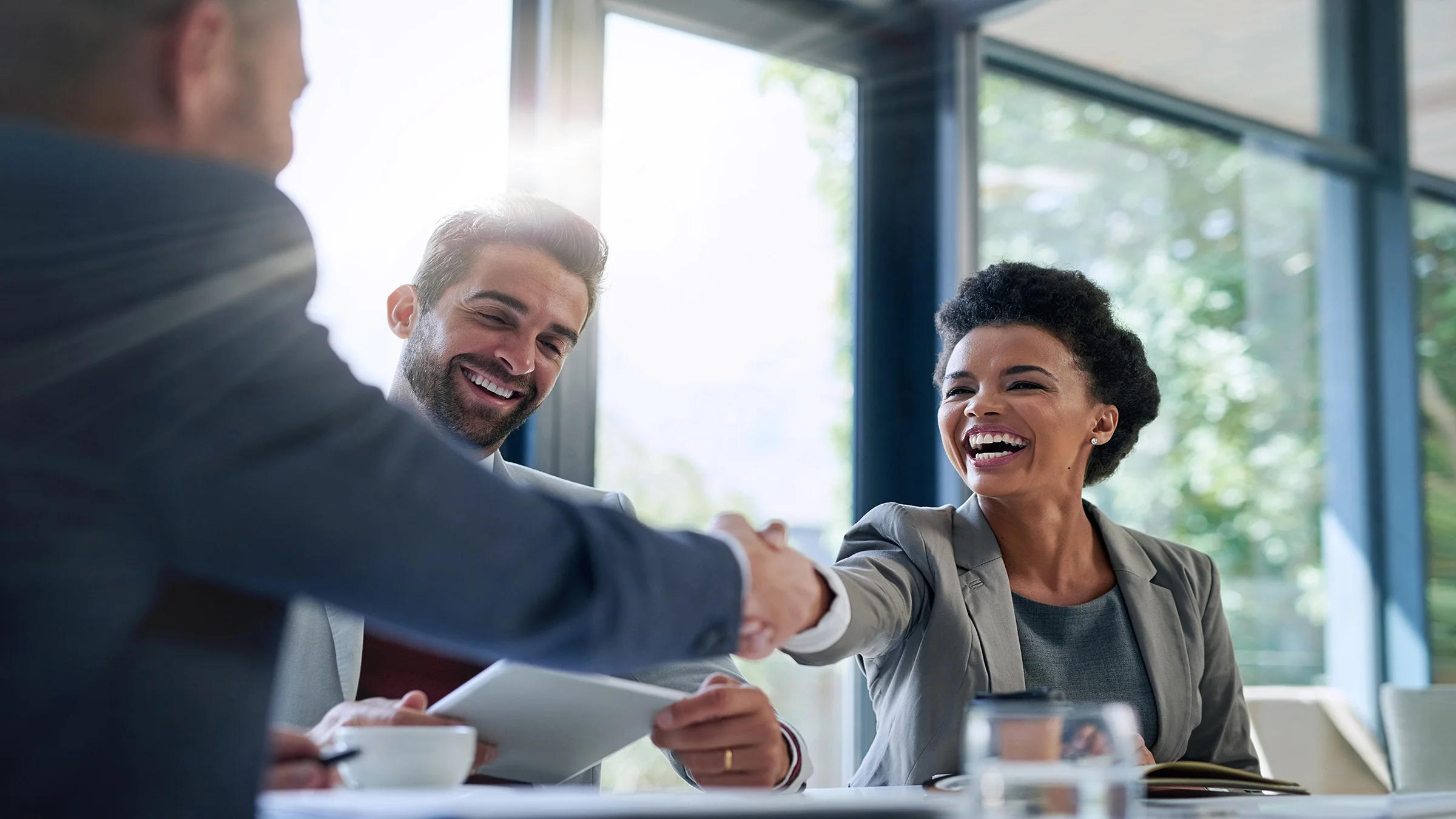 3 people in a meeting, two are shaking hands