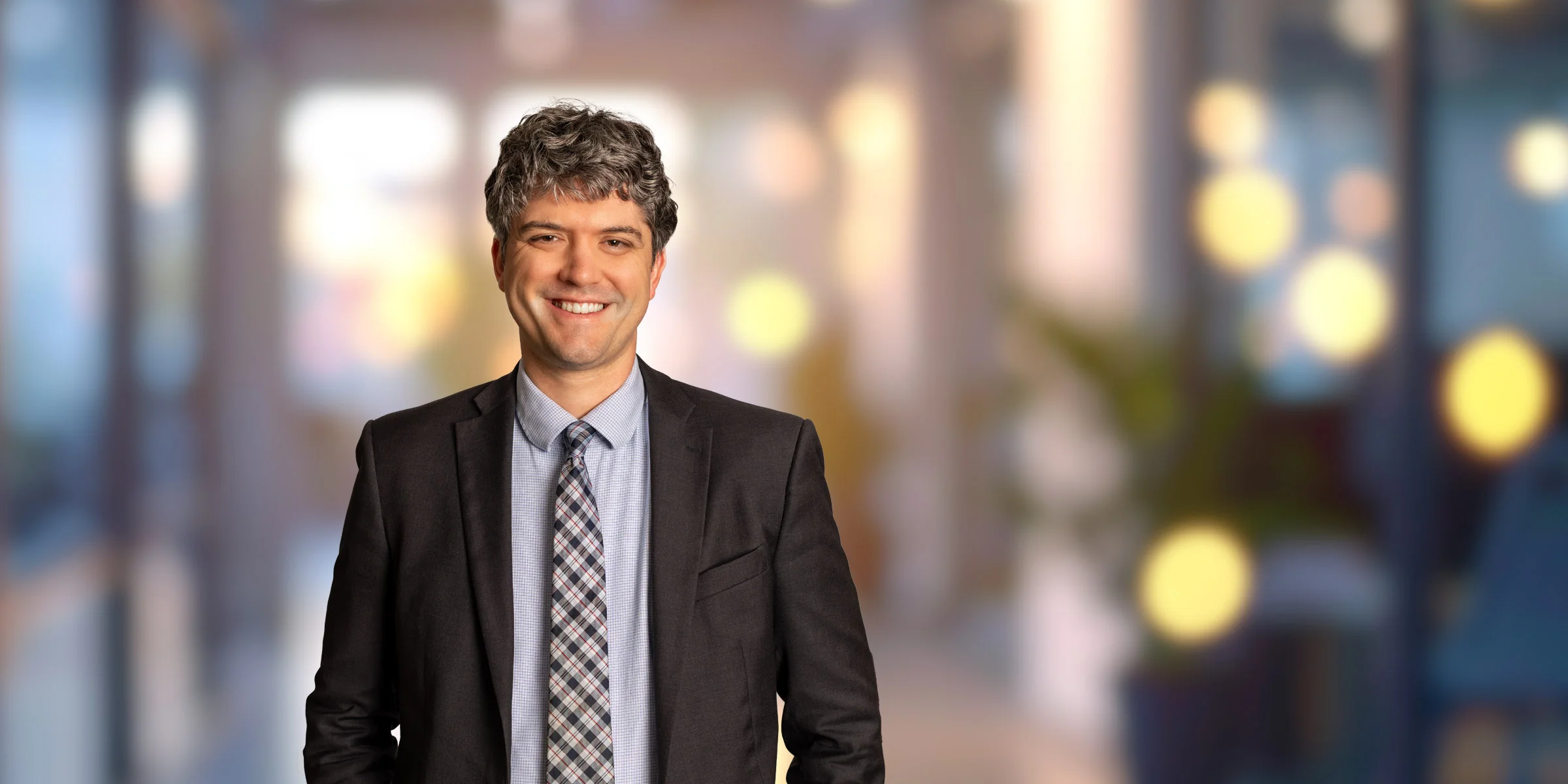 Adam Pratt smiling with a dark suit and a blue shirt
