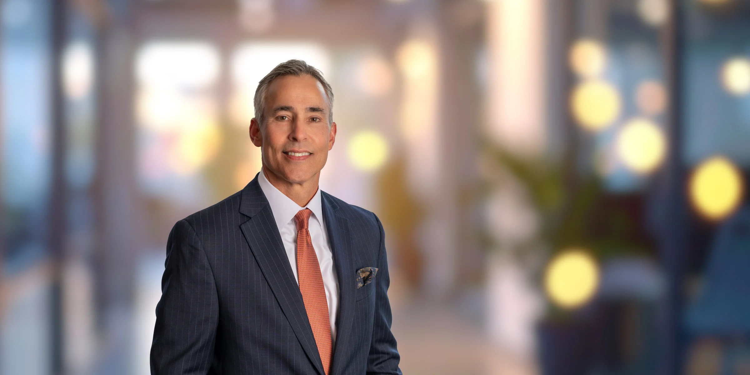 Mark Short in a dark suit and orange tie