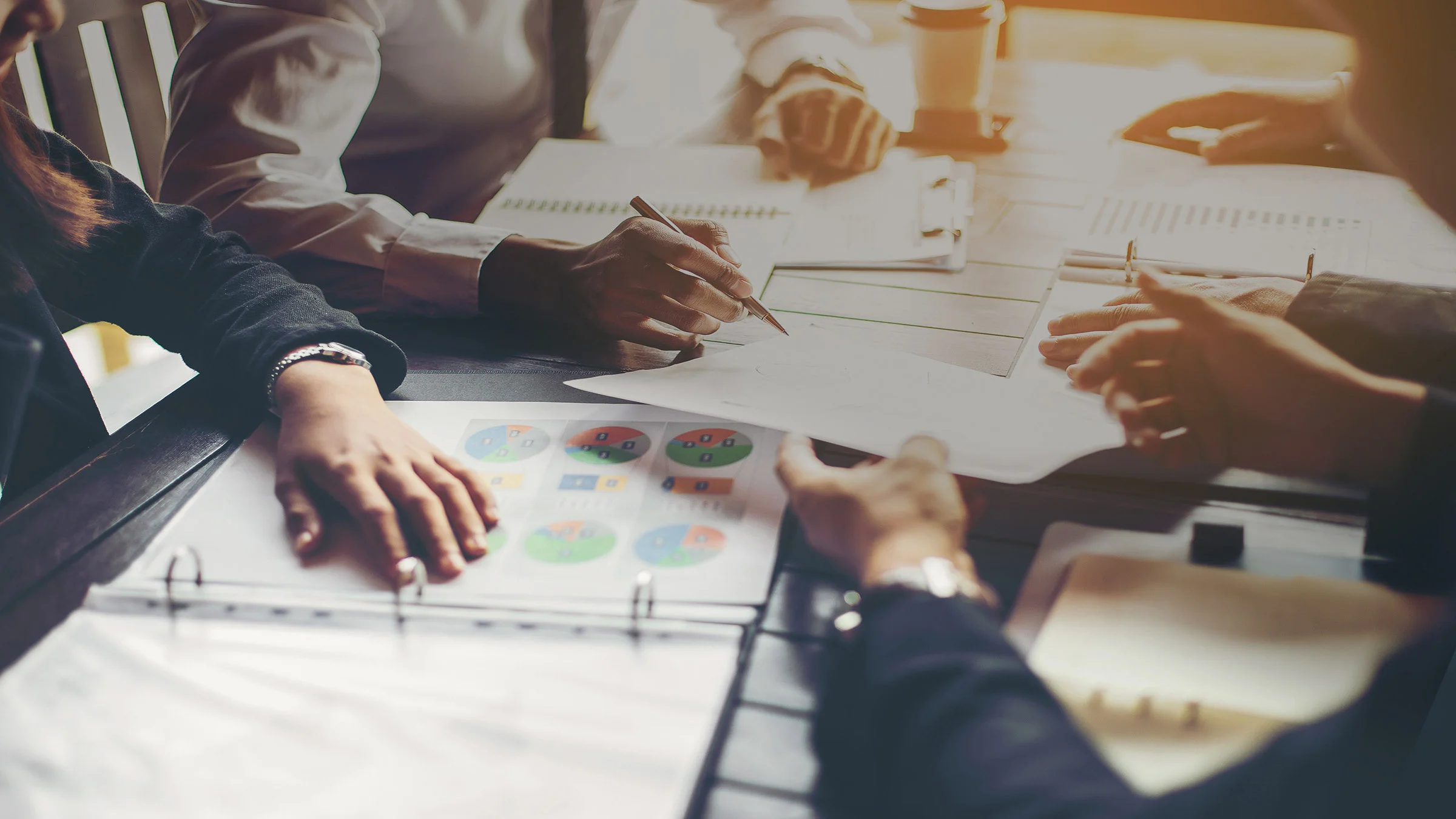Hands gathered around a conference table with papers in the middle