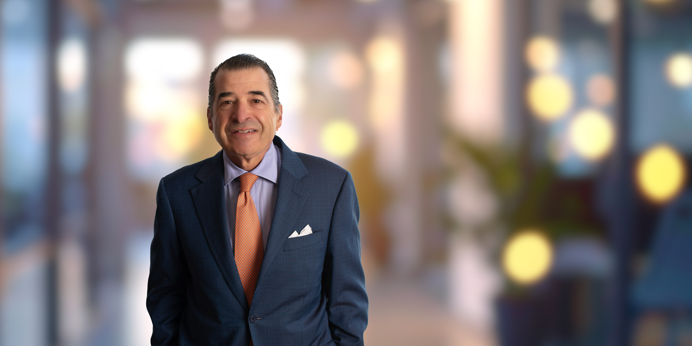 Ray Suttle wearing a blue suit and orange tie