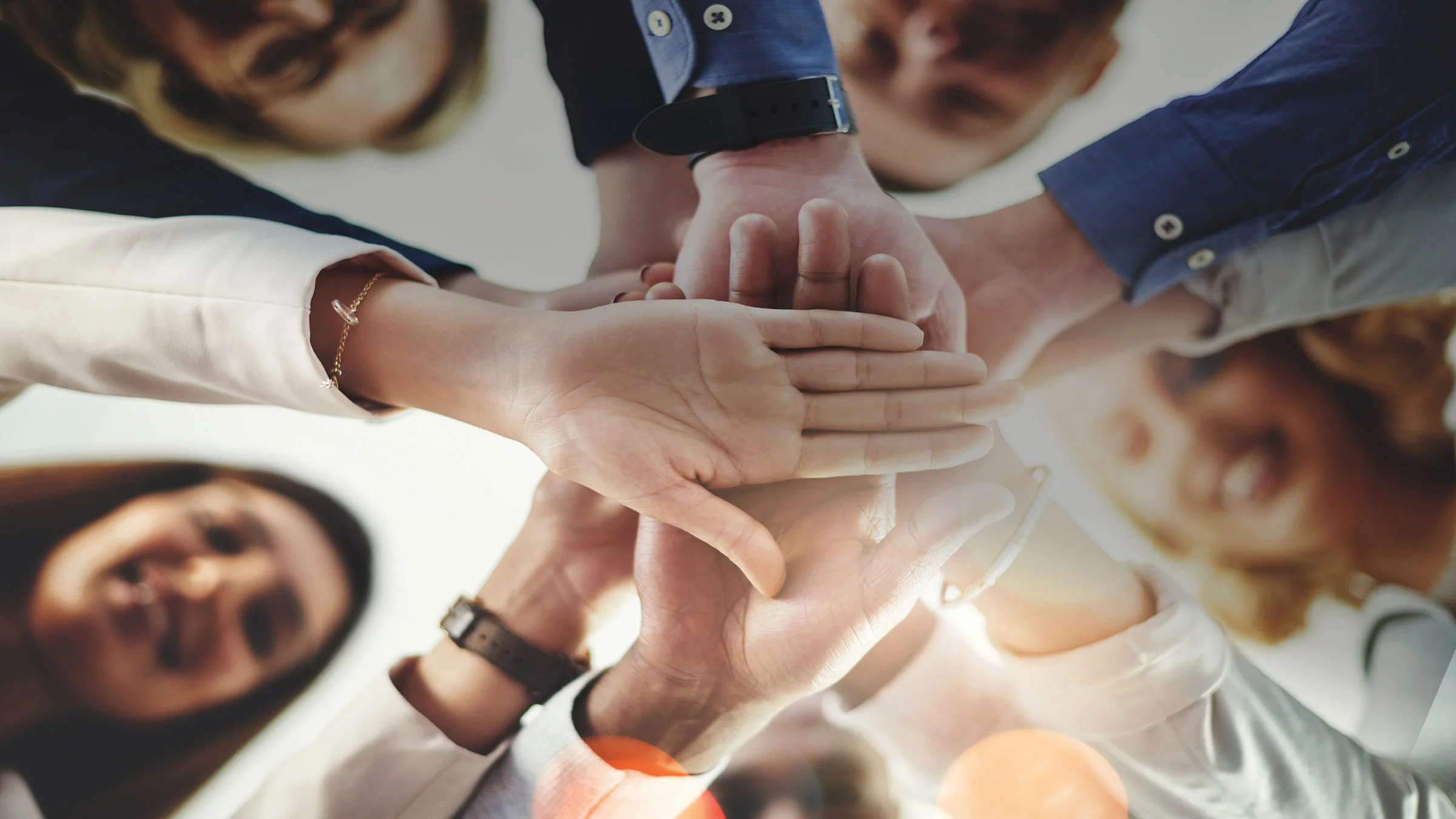 Group of people with their hands in the middle of a circle