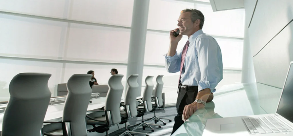 Man on phone standing in empty meeting room
