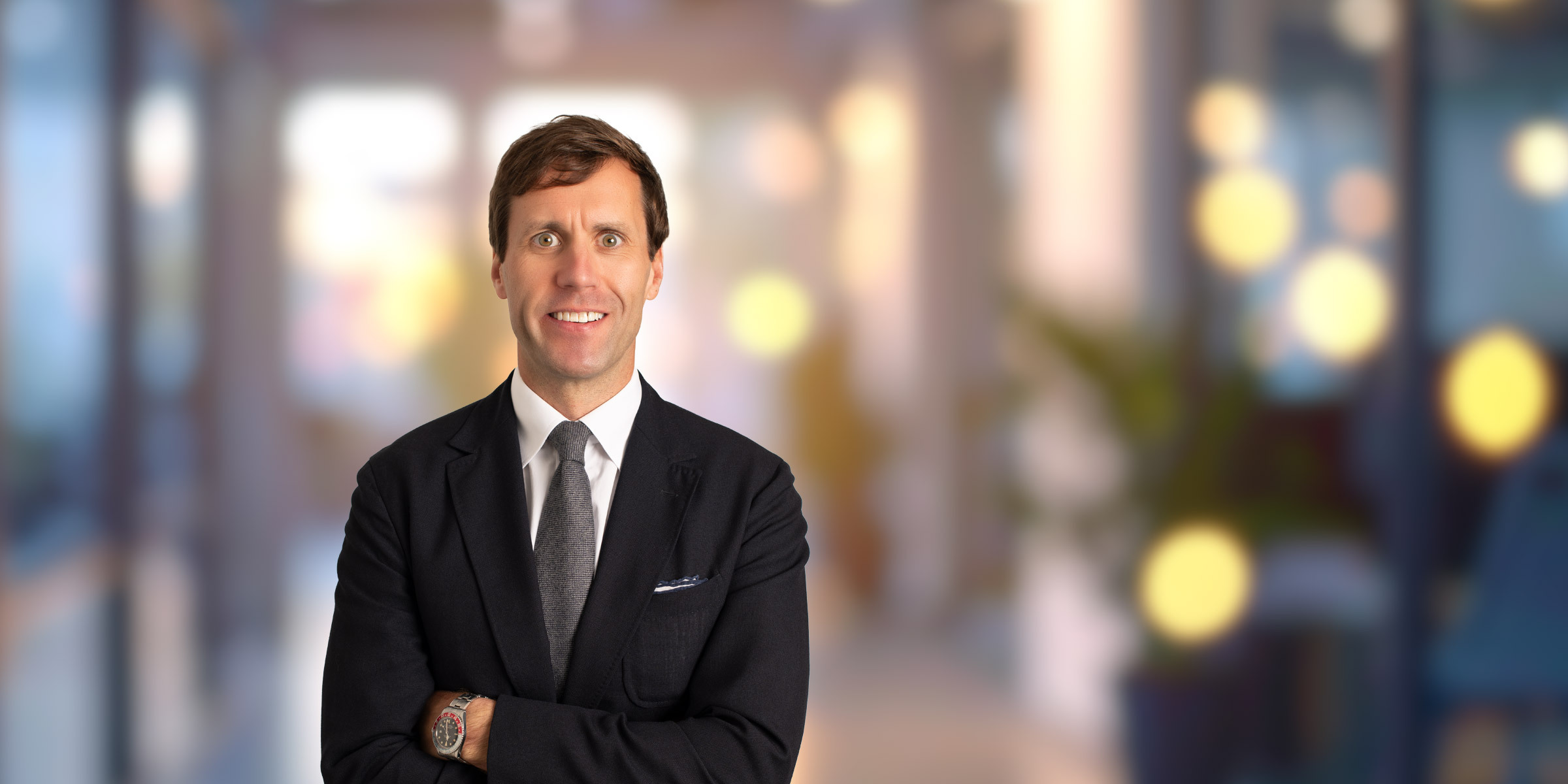 Smiling Britton Williston in a suit with his arms crossed