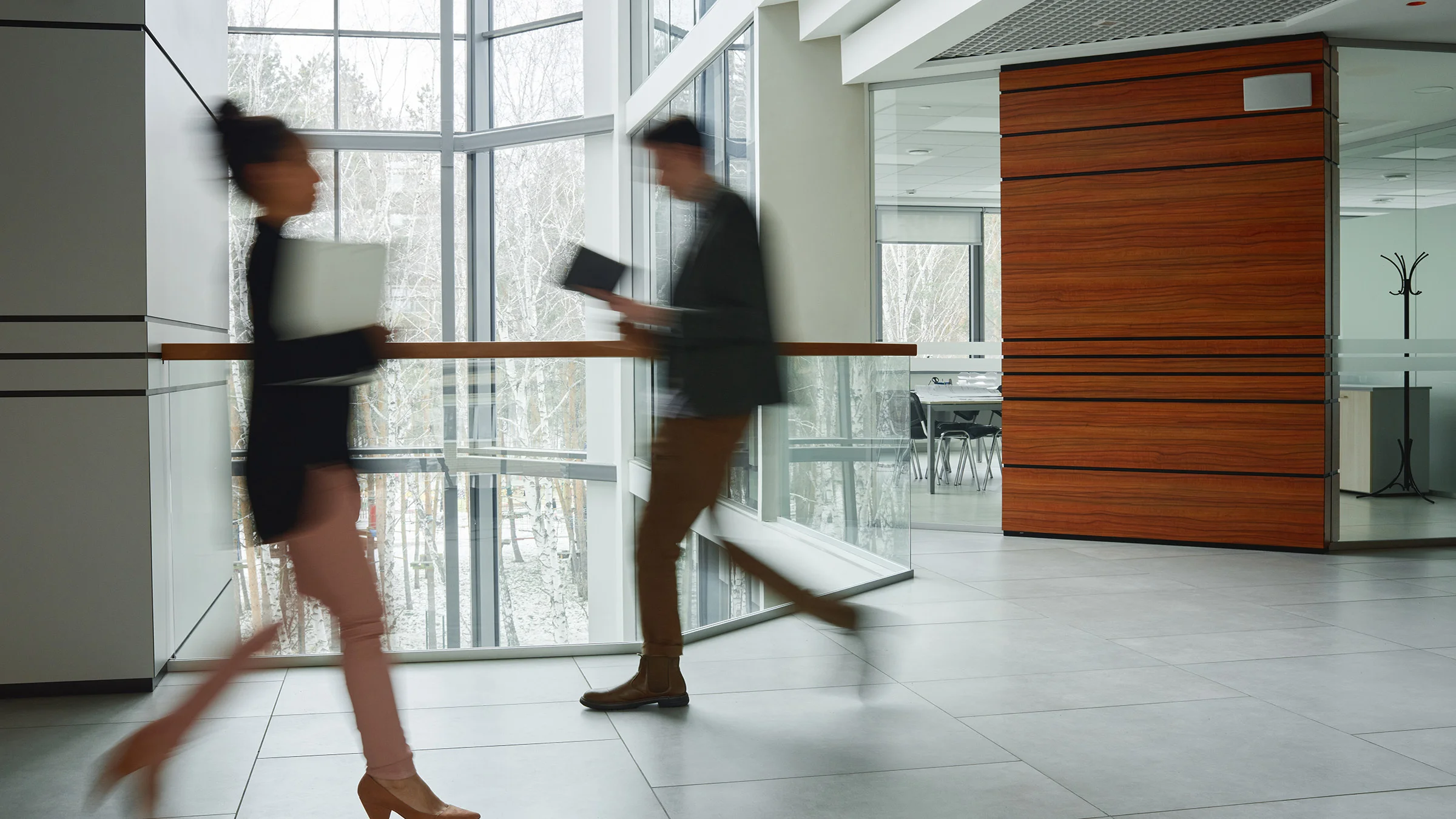 2 blurred people walking through a business lobby