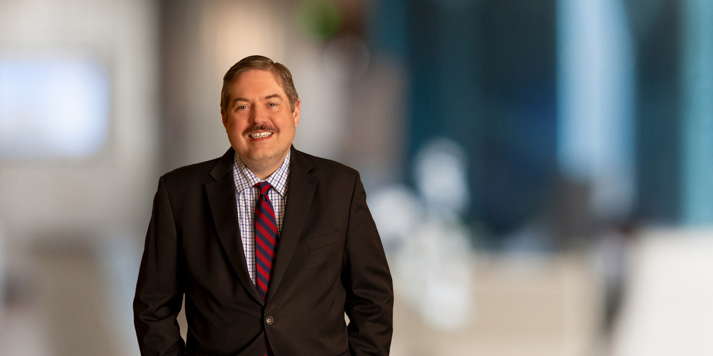 Smiling David Damiani in a dark suit and red tie