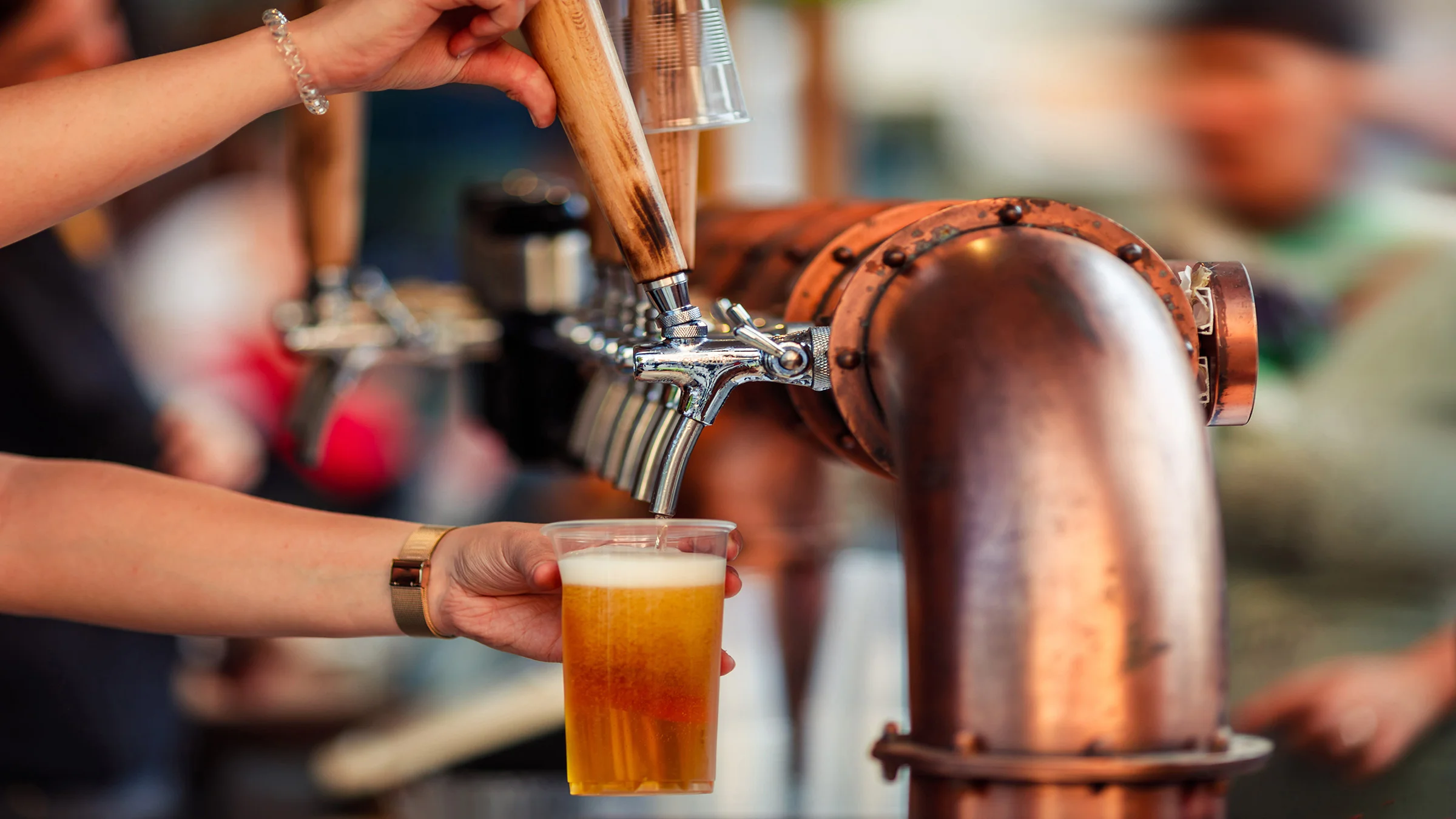 Hands pulling a beertap to pour into a glass