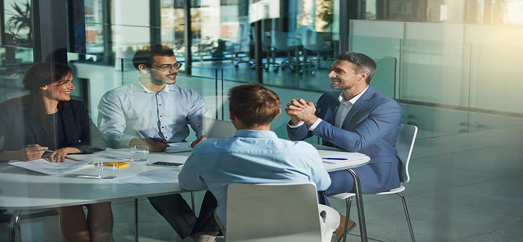 4 people around a conference room table talking