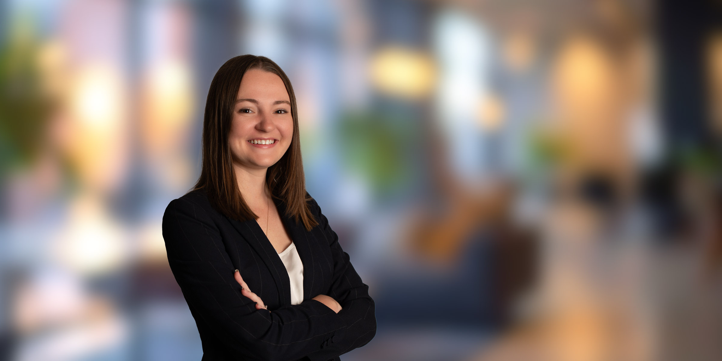 Kelsey Kita standing in a suit with her arms crossed
