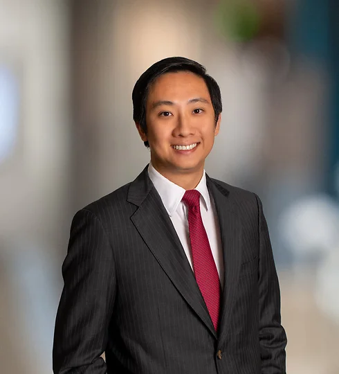 Benny Zhang in a dark suit and red tie