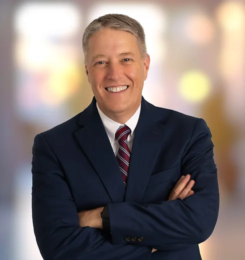 Scott Seymour smiling in a dark blue suit with a red tie