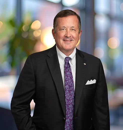Smiling Doug Foley in a black suit and purple tie
