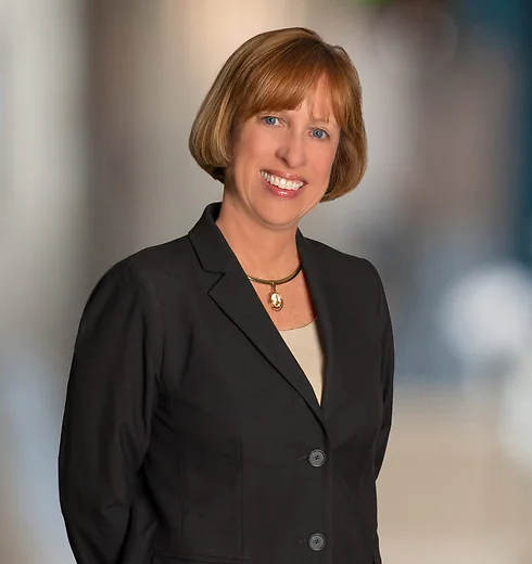 Susanna Hickman smiling with hands behind her back, in black blazer