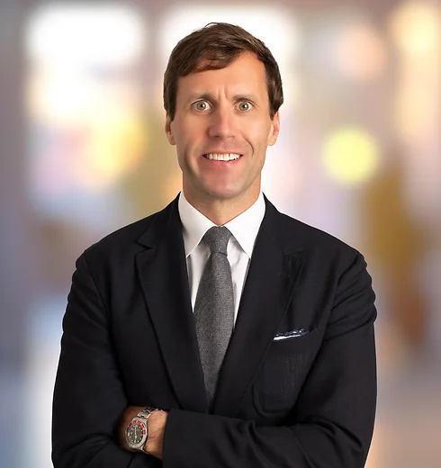 Smiling Britton Williston in a suit with his arms crossed