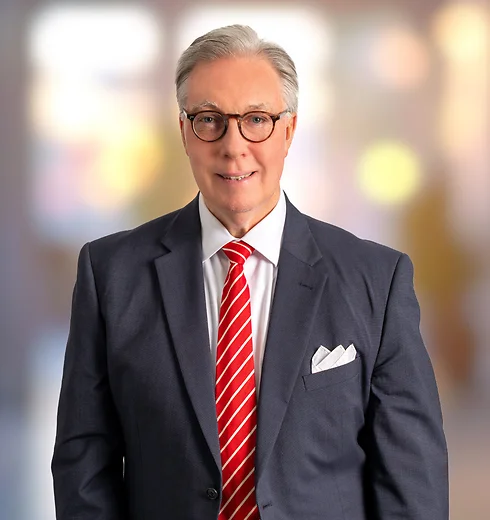 Jim Windsor wearing a dark suit and striped red tie
