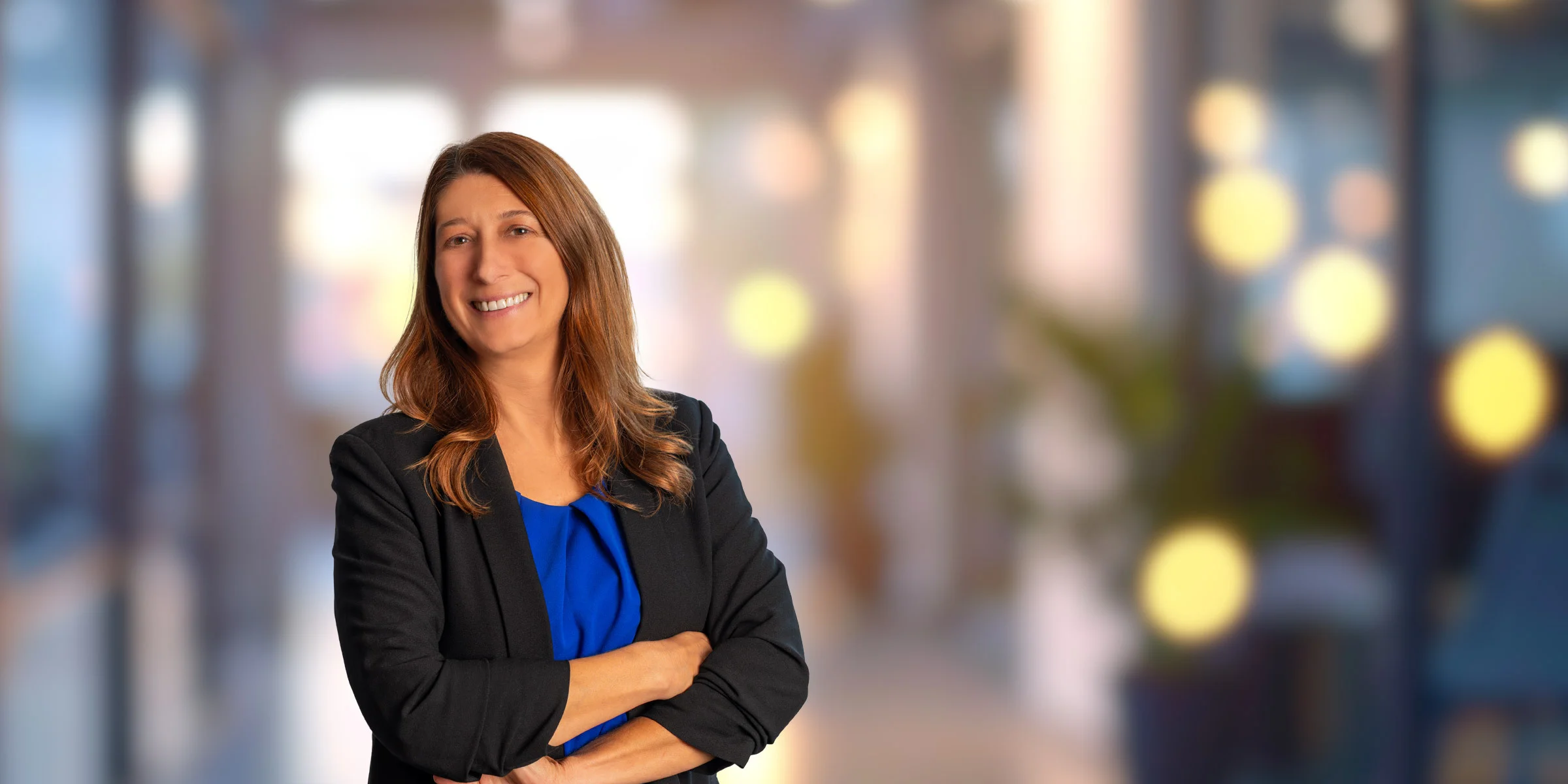 Sarah Messersmith in a blue shirt and a black suit jacket with a hand on her hip
