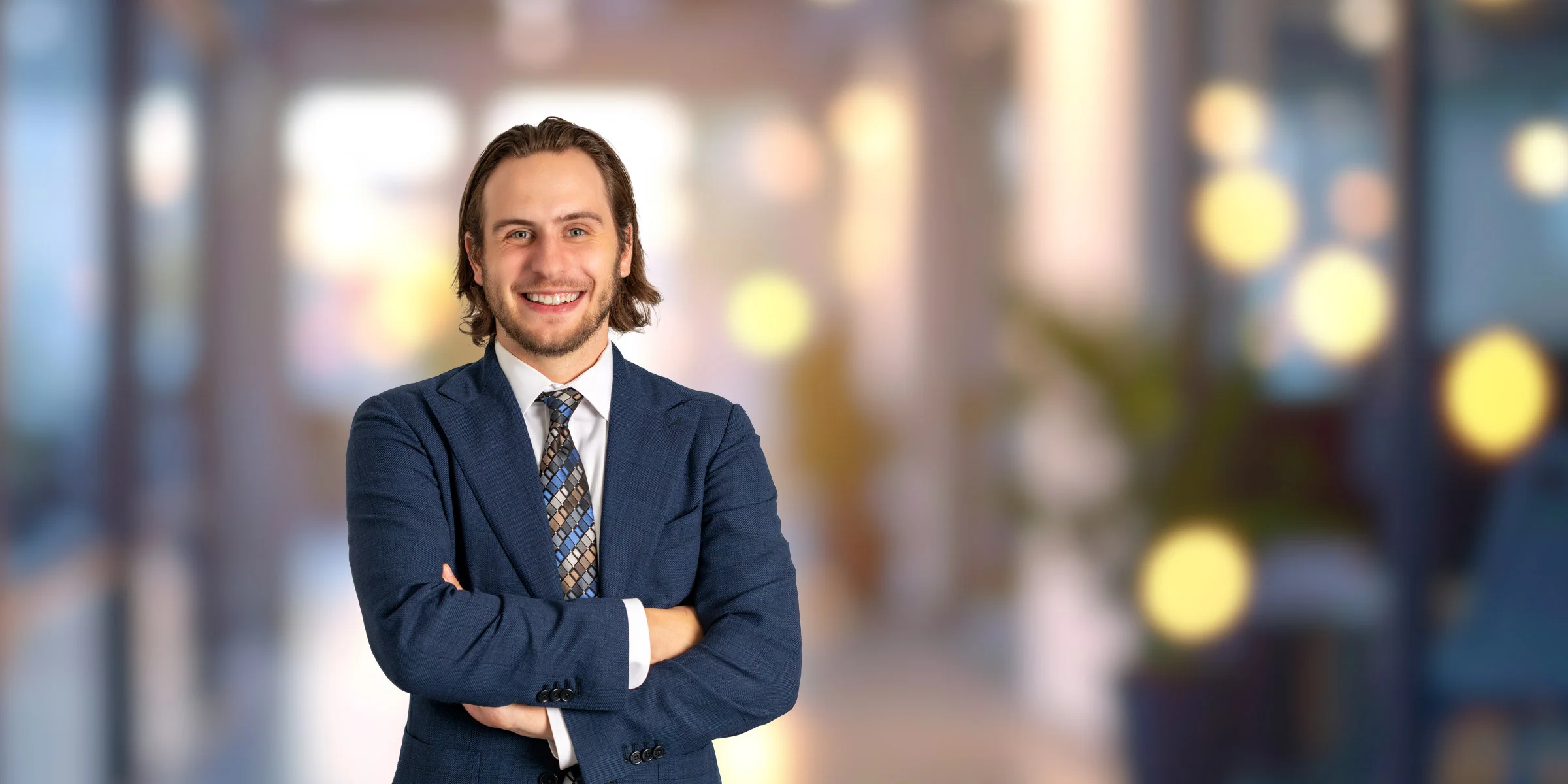 Smiling Brandan Goodwin in a dark blue suit with his arms crossed