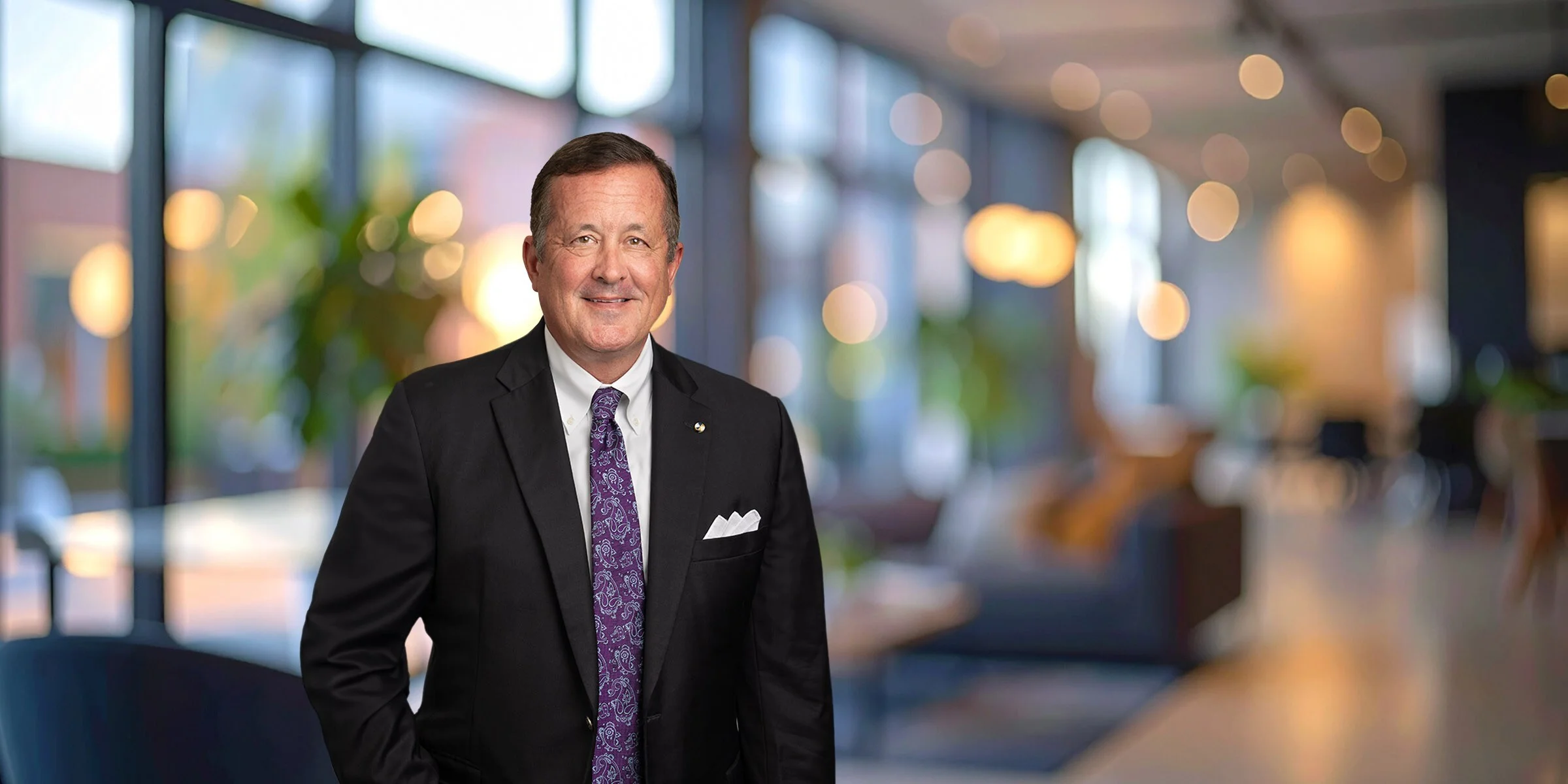 Smiling Doug Foley in a black suit and purple tie