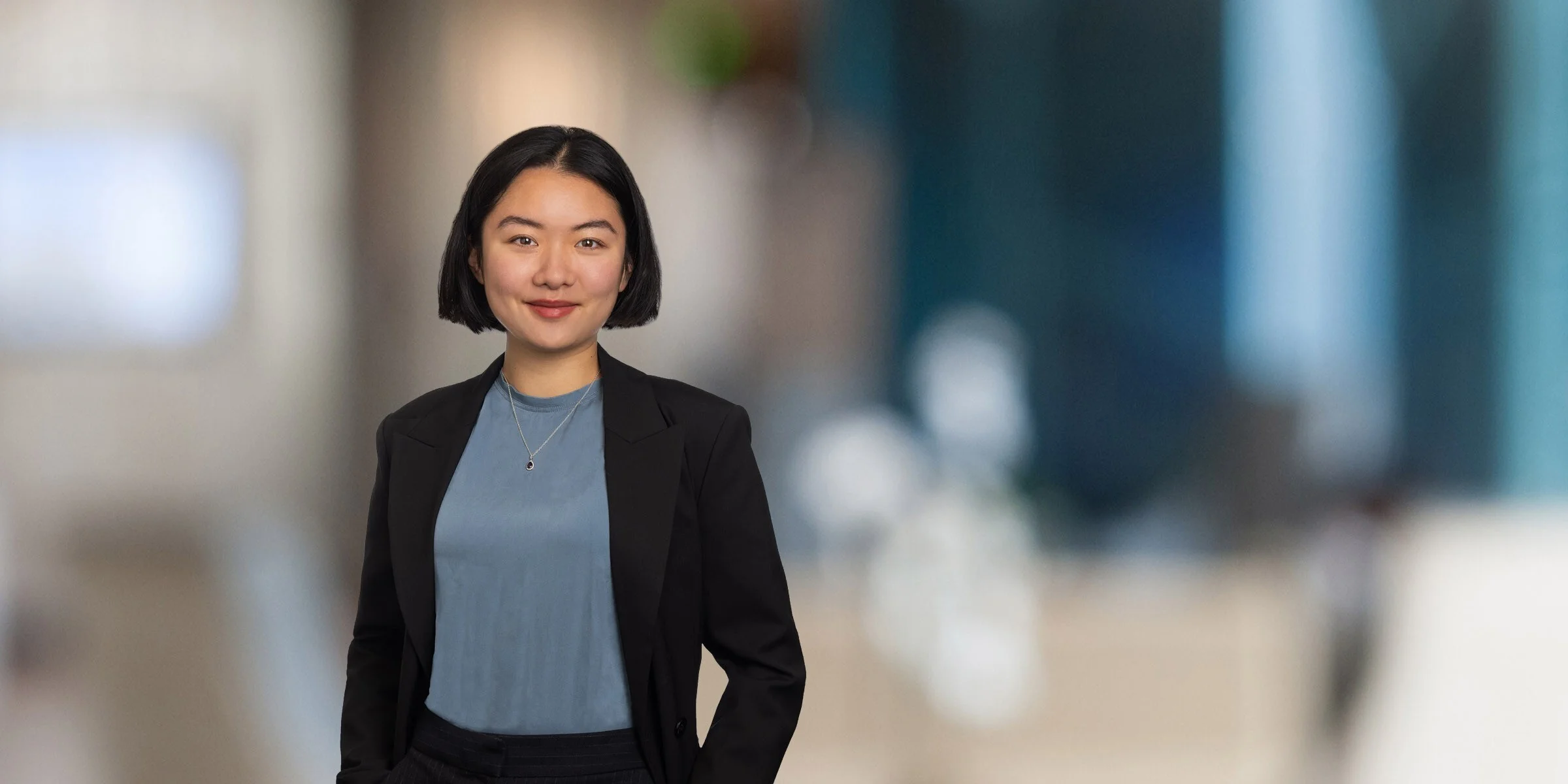 Jenny Wang in a blue shirt and black jacket with one hand in her pocket