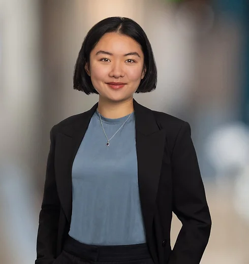 Jenny Wang in a blue shirt and black jacket with one hand in her pocket