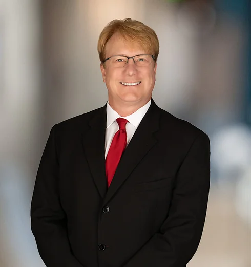 Smiling Ed Roney in a black suit and red tie
