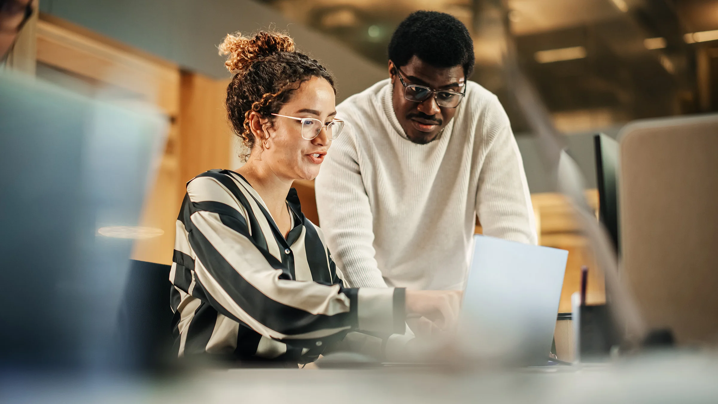 2 people pointing at a laptop