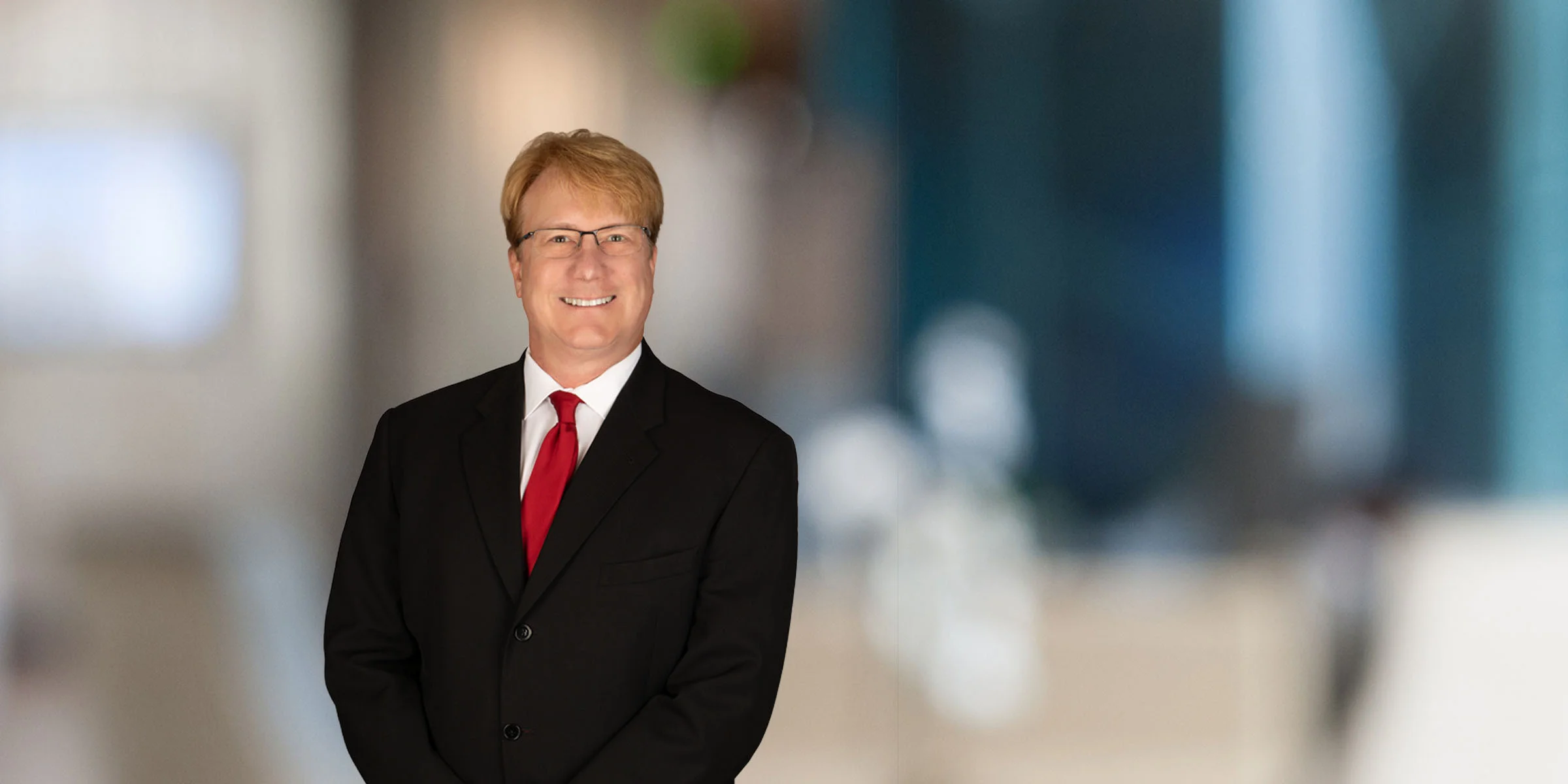 Smiling Ed Roney in a black suit and red tie