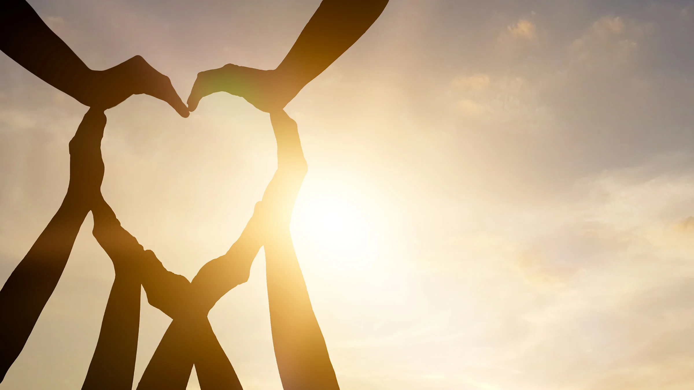 Many hands making a heart shape in the sky