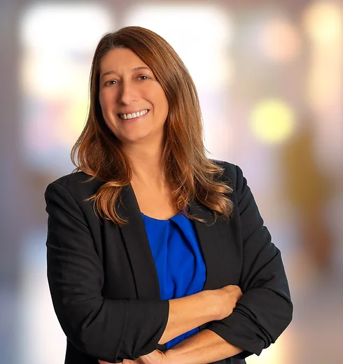 Sarah Messersmith in a blue shirt and a black suit jacket with a hand on her hip