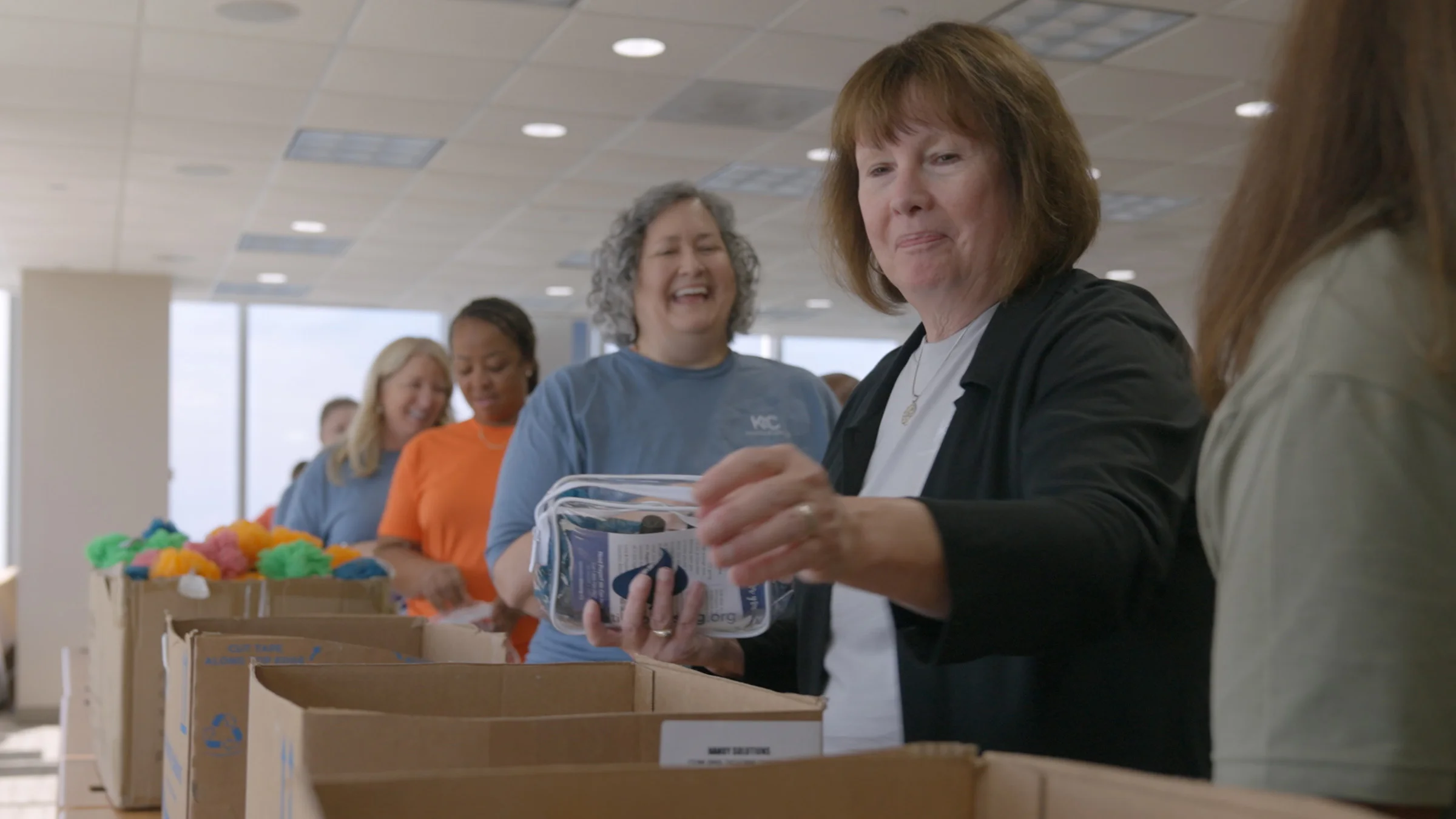 K&C employees in an assembly line filling bags for charity