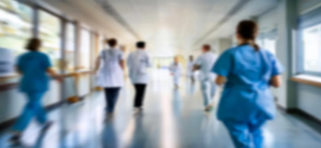 HBlurry group of doctors and nurses walking away down a hospital hallway