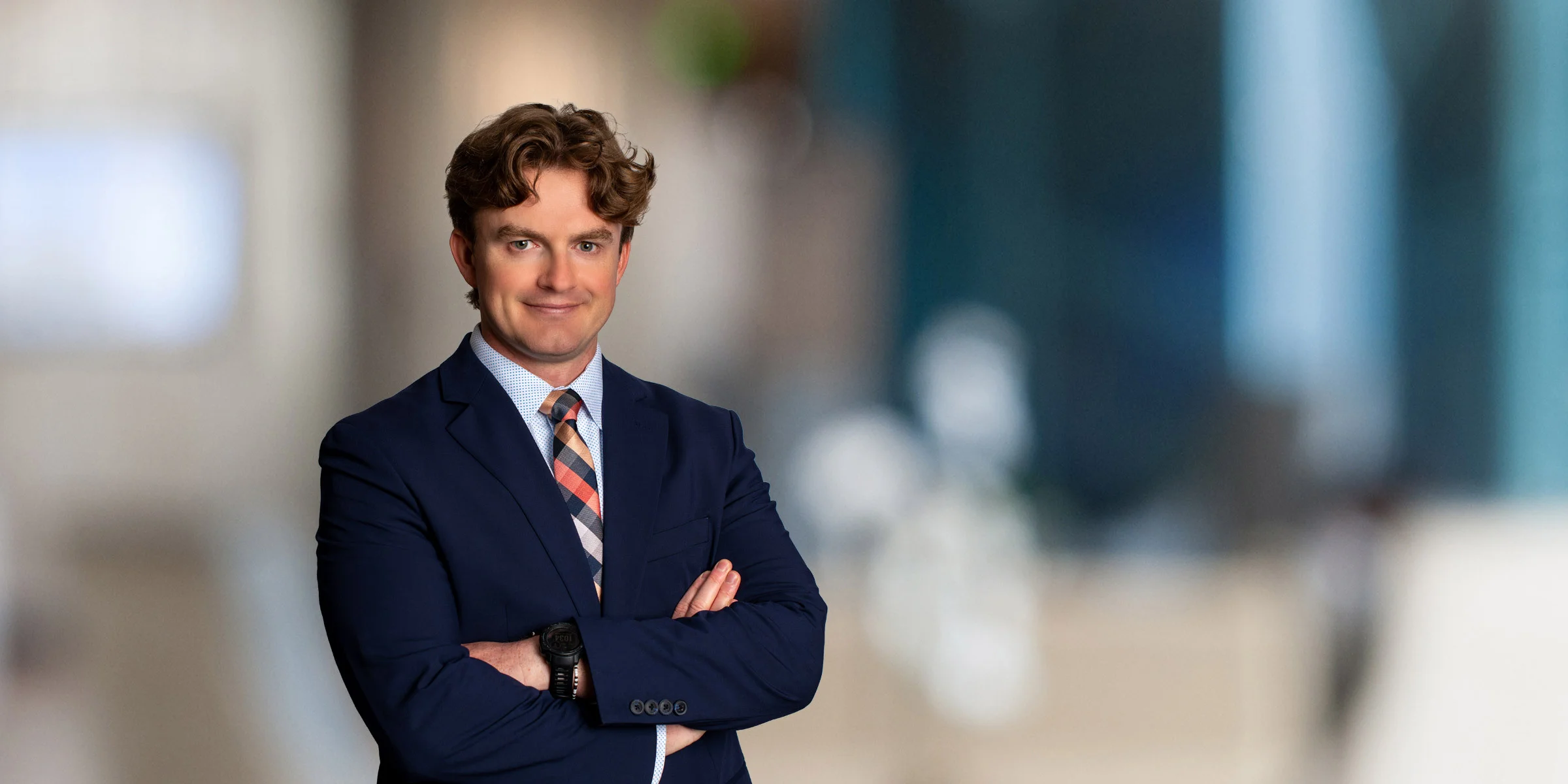 Cameron Dunnavant with his arms crossed, in a black suit and plaid tie