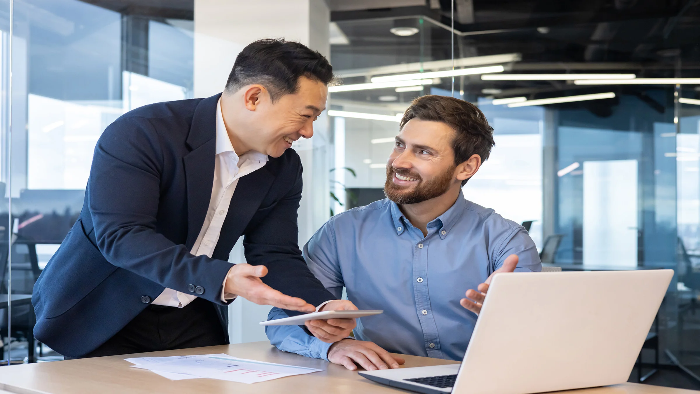 2 business men talking near a laptop