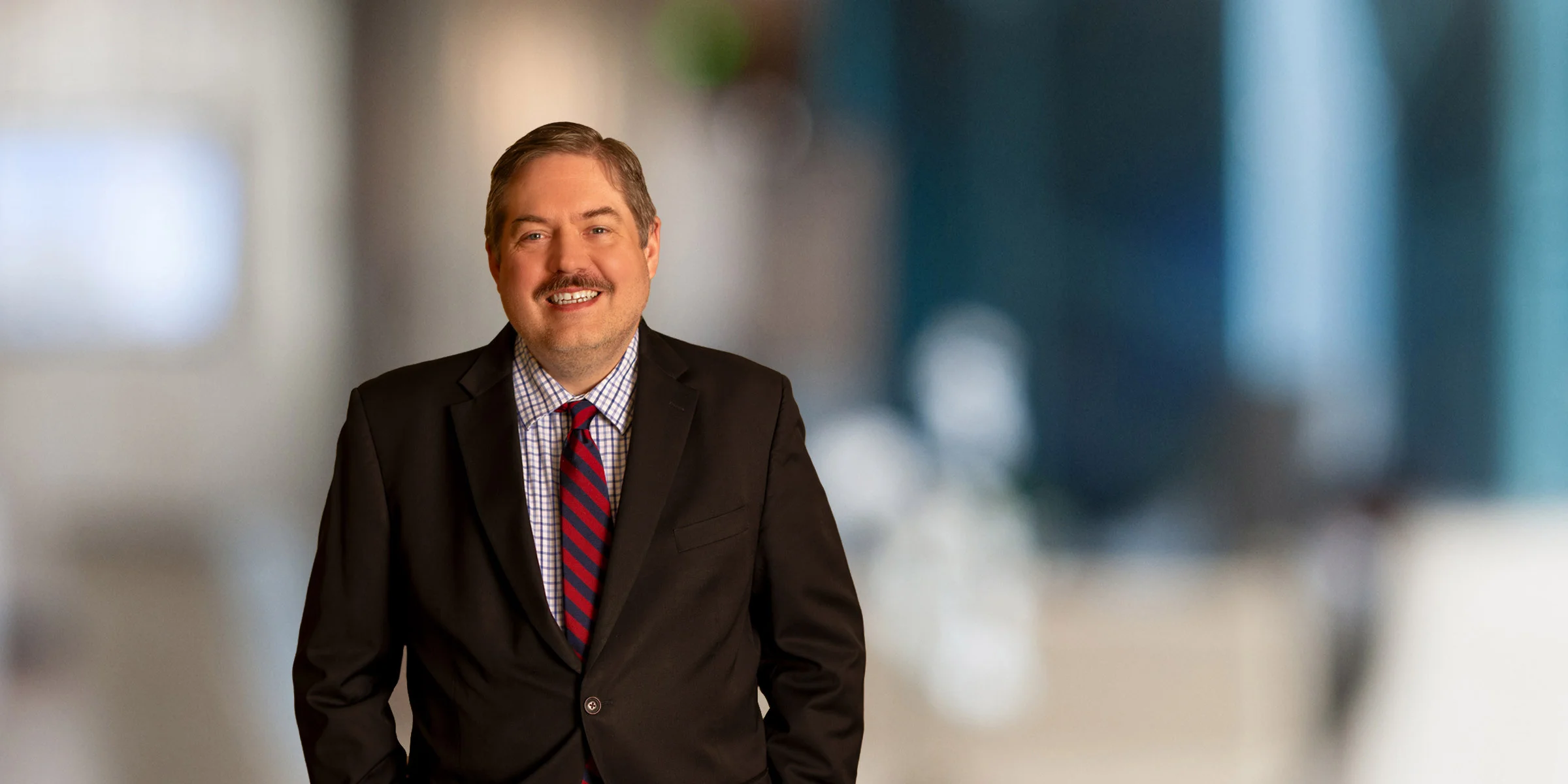 Smiling David Damiani in a dark suit and red tie