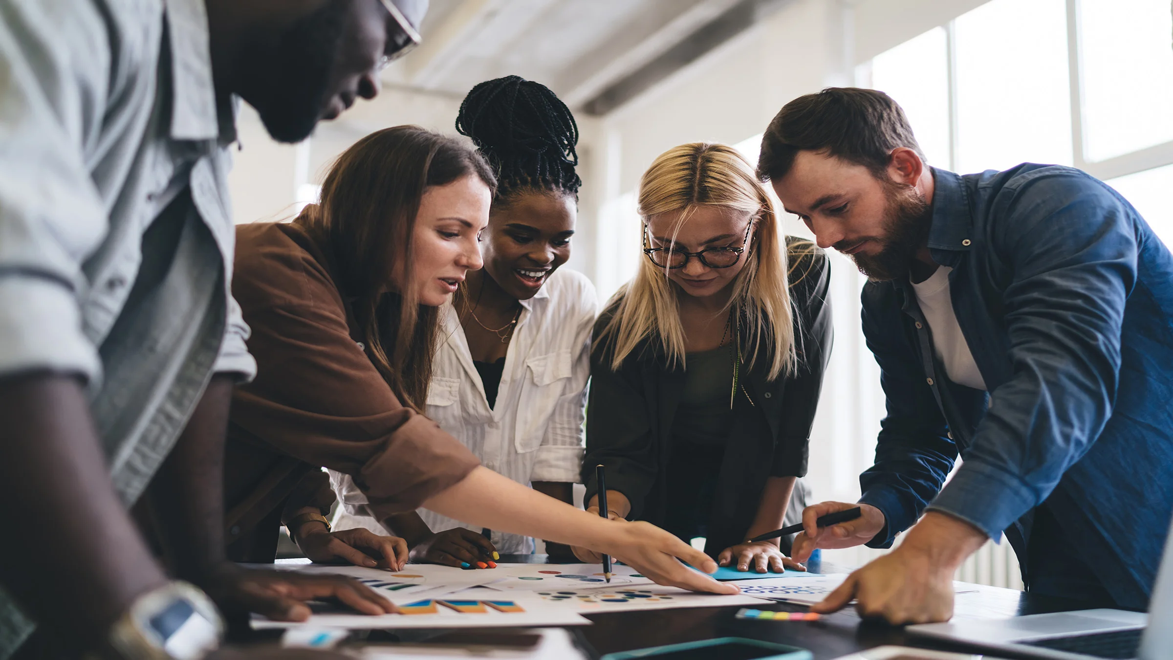 Group of people leaning over a meeting table