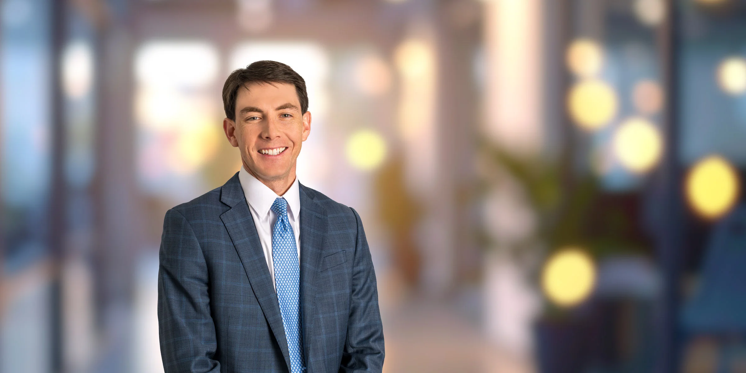Daniel Yates in plaid suit jacket and blue patterned tie