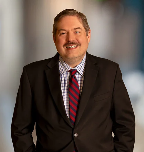 Smiling David Damiani in a dark suit and red tie
