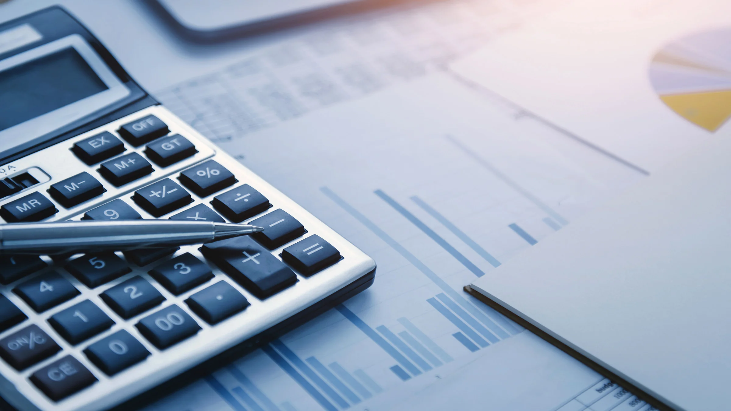 Calculator, pen and graphs on desk